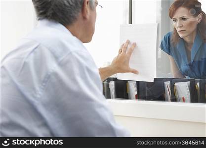 Businessman Holding Document For Businesswoman To Read