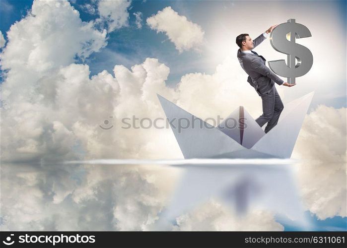 Businessman holding dollar riding paper ship boat