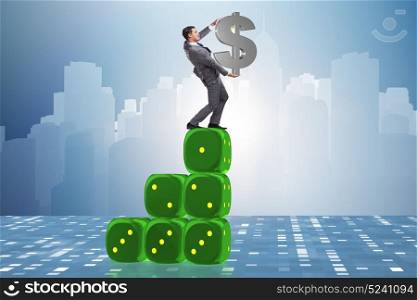 Businessman holding dollar sign on top of dice pyramid