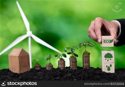 Businessman holding ECO symbol with seedling on coin stack and wind turbine. Corporate responsibility and green ecology using sustainable energy concept to reduce pollution and CO2 emission. Alter. Businessman holding ECO symbol with seedling on coin stack. Alter