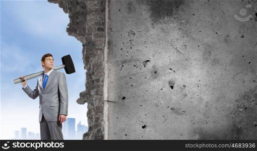 Businessman holding hammer. Young determined businessman with big hammer in hands