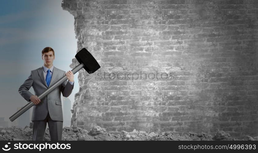 Businessman holding hammer. Young determined businessman with big hammer in hands