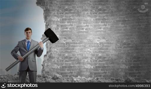 Businessman holding hammer. Young determined businessman with big hammer in hands
