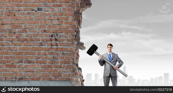 Businessman holding hammer. Young determined businessman with big hammer in hands