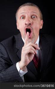 Businessman holding index finger at his mouth. Silence gesture