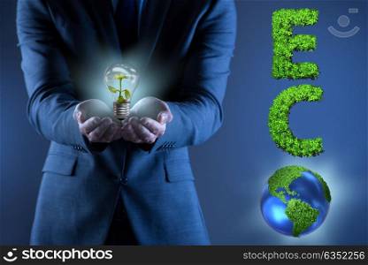 Businessman holding lamp in green environment concept