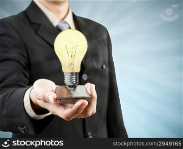 Businessman holding mobile phone light bulb coming out technology, and new ideas concept