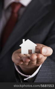 Businessman Holding Model House In Palm Of Hand