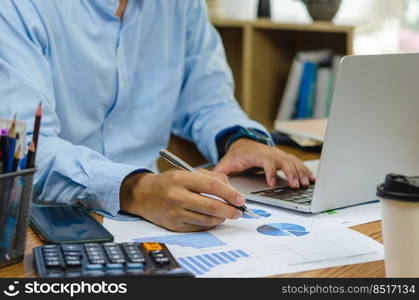 Businessman holding pen document graph accounting finance paper work analysis chart marketing investment and report economy with computer laptop on desk at office.