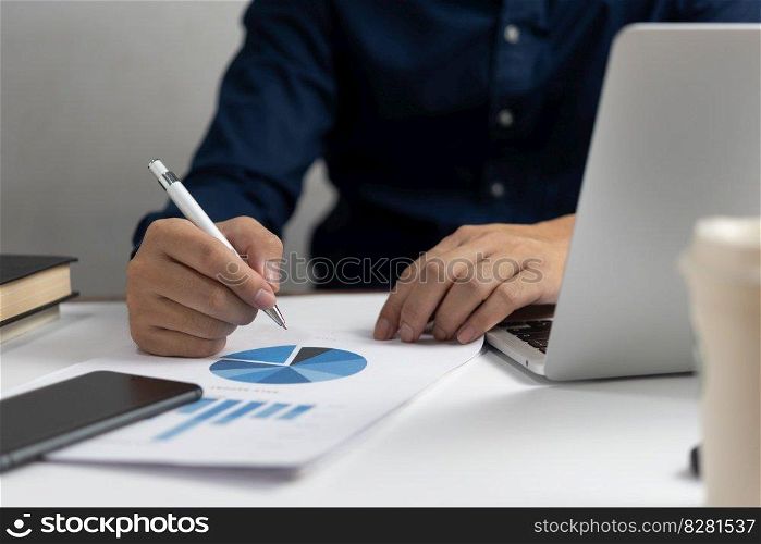Businessman holding pen document graph and chart holding pen accounting marketing with computer laptop.