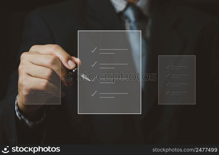 businessman holding pen to check business digital documents on virtual screen.