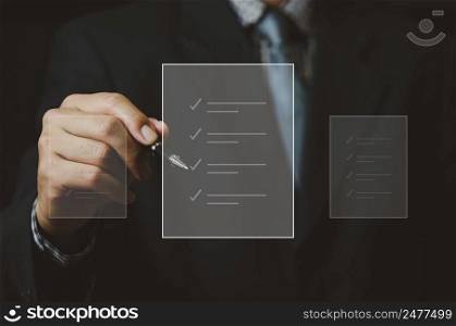 businessman holding pen to check business digital documents on virtual screen.