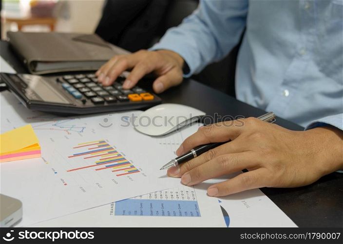 Businessman holding pen to look at business, financial, tax, budget analysis and marketing documents.
