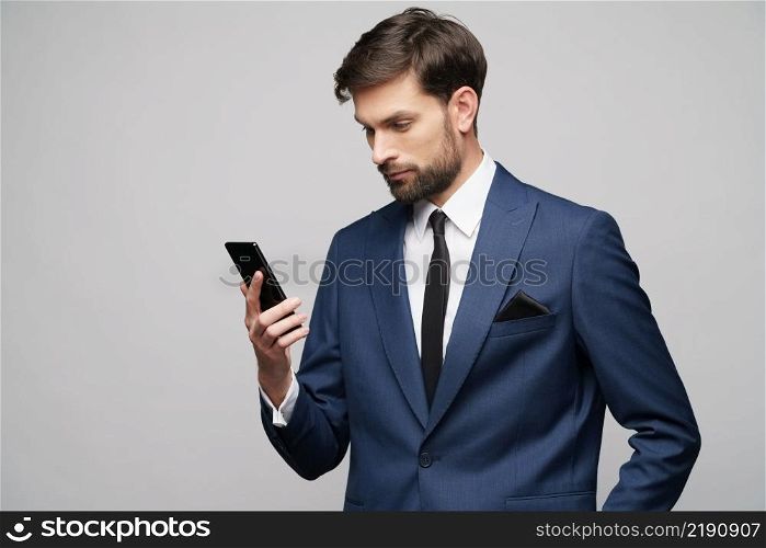 businessman holding phone isolated over grey background in studio shooting. businessman holding phone isolated over grey background