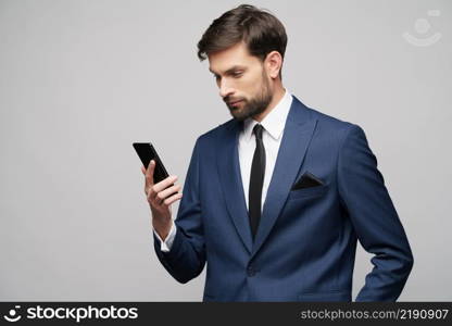 businessman holding phone isolated over grey background in studio shooting. businessman holding phone isolated over grey background