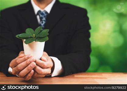 Businessman holding plant pot with his hand promoting forest regeneration and natural awareness. Ethical green business with eco-friendly policy utilizing renewable energy to preserve ecology. Alter. Businessman holding plant pot with his hand promoting forest regeneration. Alter