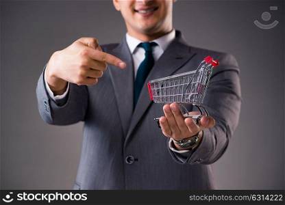 Businessman holding shopping cart in business concept