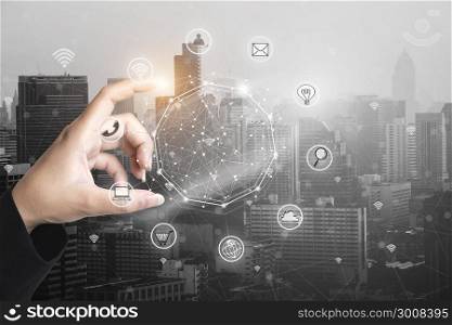 Businessman holding smart phone with wireless communication network icon and cityscape background.E-commerce smart connection business. internet of things.