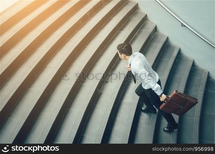 Businessman holding suitcase and running on stairs.