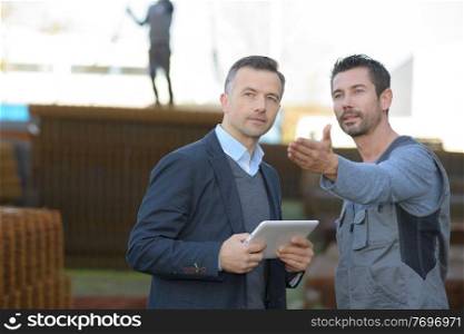 businessman holding tablet and worker pointing something