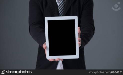 Businessman holding tablet . Businessman holding tablet in black suit on gray background