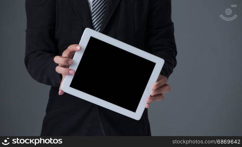 Businessman holding tablet . Businessman holding tablet in black suit on gray background