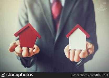 Businessman holding two houses and can not decide choosing the right house. Businessman holding two houses and can not decide choosing the right house.