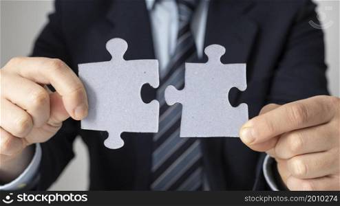 businessman holding two puzzle pieces
