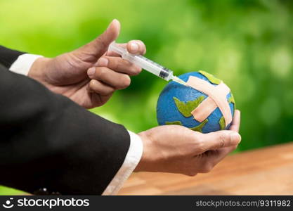 Businessman holds and inject medicine to paper earth as symbol of eco environmental awareness and healing planet earth for sustainable world with healthy ecology. Alter. Businessman holds and inject medicine to paper earth as eco awareness. Alter