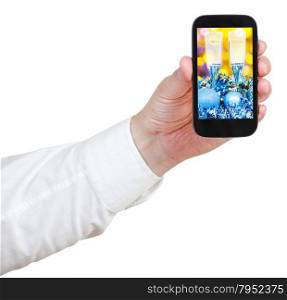 businessman holds handphone with Christmas still life on screen isolated on white background