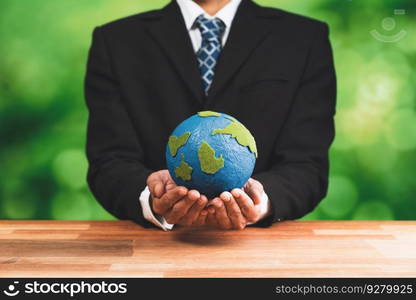 Businessman holds paper earth as symbol of eco environmental awareness for sustainable world using clean energy and zero CO2 emission. Eco-friendly corporate with go green policy to save earth. Alter. Businessman holds paper earth as symbol of eco environmental awareness. Alter