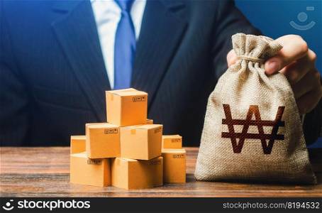 Businessman holds south korean won money bag and boxes with goods. Import and export. Business income. Payment of taxes and fees. Advertising budget. Purchase and sale of goods, trade and commerce.