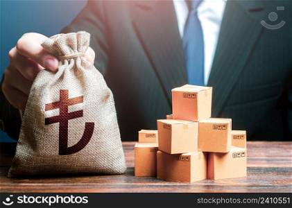 Businessman holds turkish lira money bag and boxes with goods. Business income. Payment of taxes and fees. Advertising budget. Purchase and sale of goods, trade and commerce. Import and export.