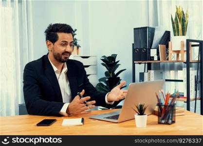 Businessman holds virtual office meeting from desk, discussing with remote workers via video conference using webinar application on laptop for distant office working concept. Fervent. Businessman holds virtual office meeting from desk. Fervent
