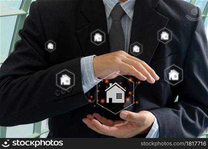 Businessman house on hand virtual screen hologram. Buying, selling and renting houses or real estate concept.Home or real estate insurance. Businessman house on hand virtual screen hologram.