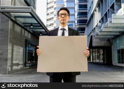 Businessman in a city street holding a blank banner. Read my message