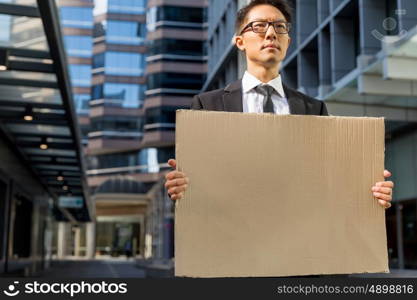 Businessman in a city street holding a blank banner. Read my message