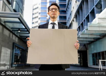 Businessman in a city street holding a blank banner. Read my message