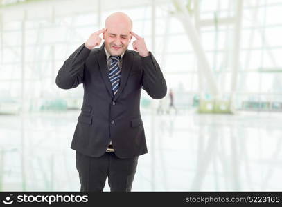 Businessman in a suit gestures with a headache, at the office