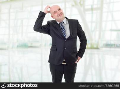 Businessman in a suit gestures with a headache, at the office