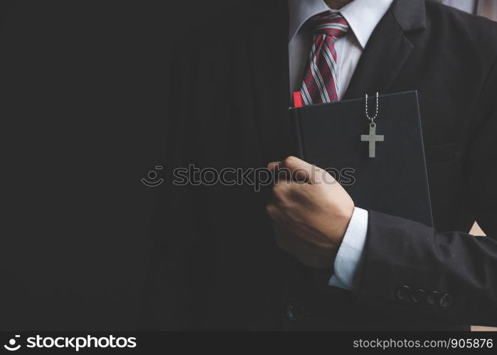 Businessman in a suit holding a bible book.