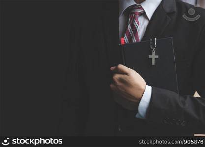 Businessman in a suit holding a bible book.