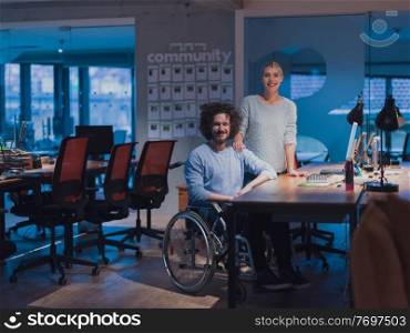 Businessman in a wheelchair in modern coworking office space working late at night in the office. Colleagues in the background. Disability and handicap concept. Selective focus. Businessman in a wheelchair in modern coworking office space working late night in office. Colleagues in background. Disability and handicap concept. 