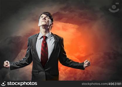 businessman in anger. businessman in anger with fists clenched looking in the sky