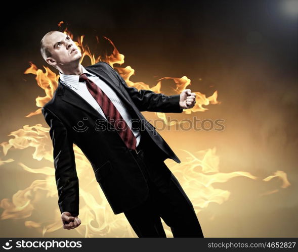 Businessman in anger. Image of young businessman in anger burning in fire