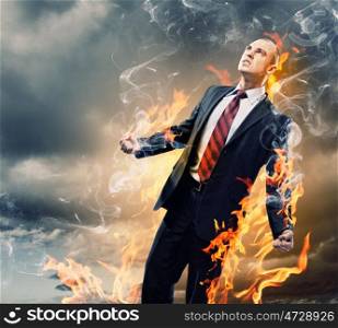 Businessman in anger. Image of young businessman in anger burning in fire
