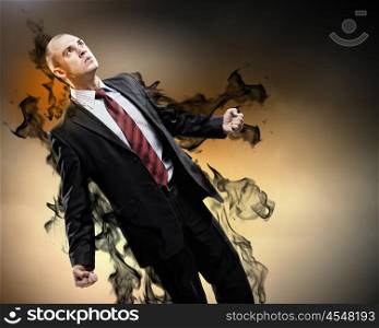 Businessman in anger. Image of young businessman in anger standing in black smoke
