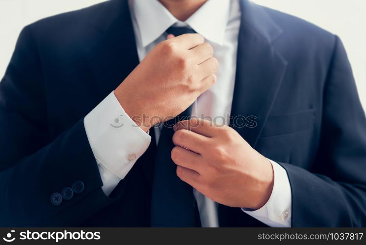 Businessman in black suit and adjusting necktie.