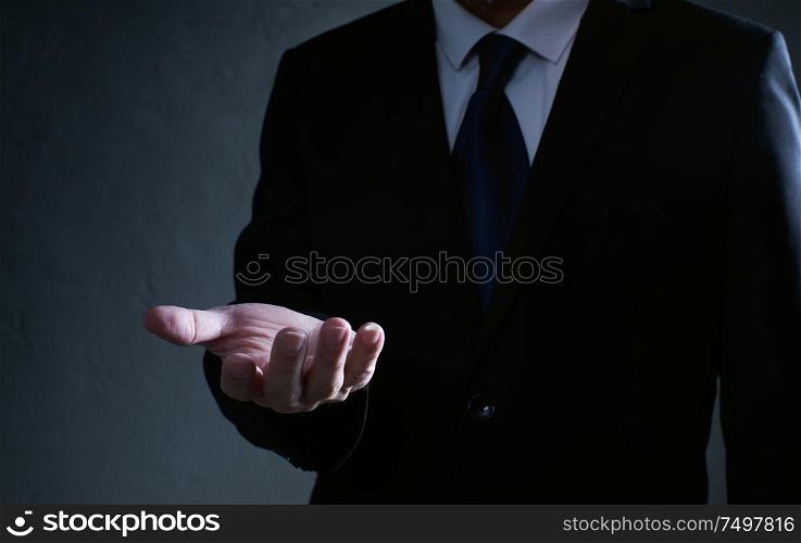 Businessman in black suit lending a helping hand, isolated on white background