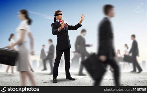 Businessman in blindfold among group of people